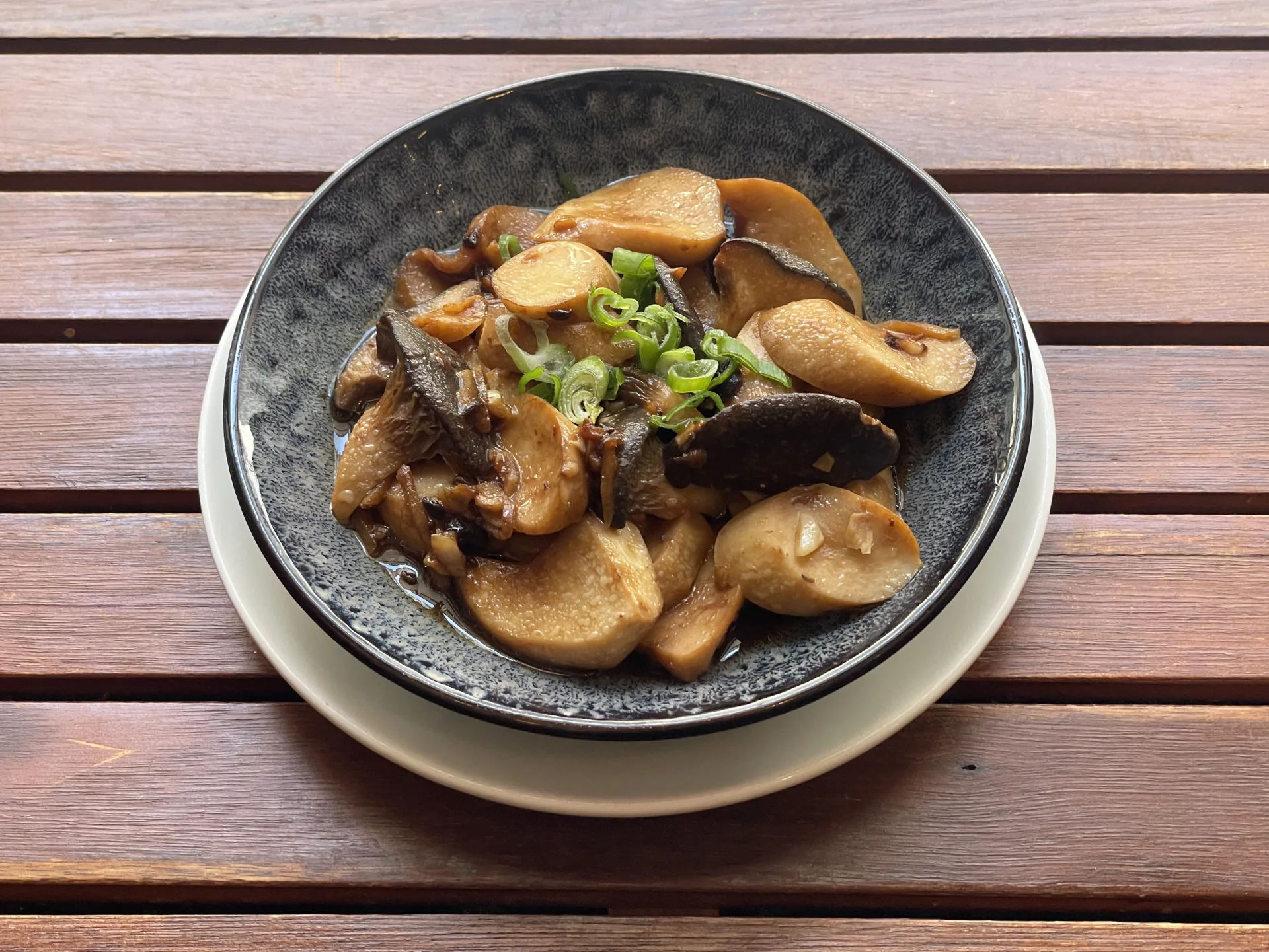 豆瓣醬蒸雞髀菇——杏鲍菇与香菇以豆瓣酱蒸制，点缀新鲜葱花，盛于日式陶碗，木质背景